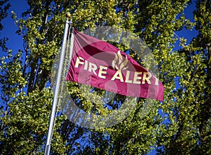 Flag in wind reading `Fire Alert`with aspen trees in background photo